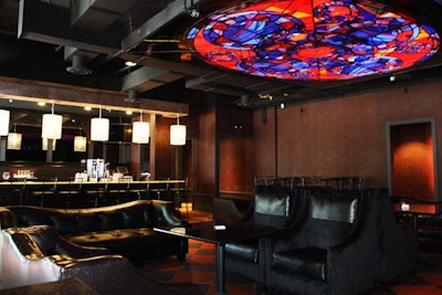 Above the lounge area, a large stained-glass light fixture alternates between shades of red and blue.