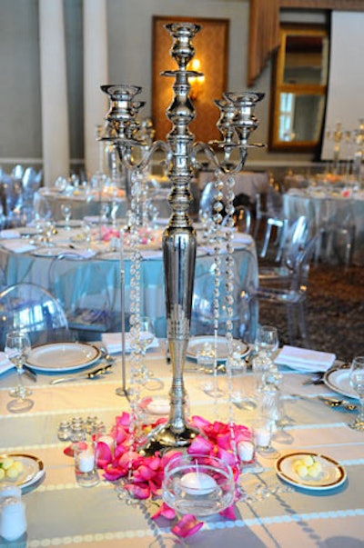 Silver candlesticks, crushed rose petals, and hanging crystals decorated tabletops.