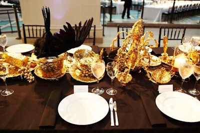 Angel Otero looked to create irony by choosing to design a centerpiece that looked like the remains of a dinner party. Covered in gold, the messy arrangement of glassware, cups, plates, and bowls also featured crows.