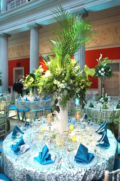 Tall arrangements of palm fronds, white calla lilies, and other greenery topped the tables on the first floor.