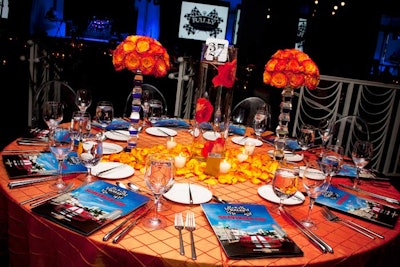 For the gala, Blooming Design & Events decorated the tables with two crystal pillars topped with balls of Voodoo roses, a cylinder vessel filled with wired roses submerged in water, and a scattering of rose petals and votive candles.