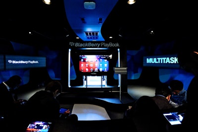 The interior of the PlayBook tour truck is designed like a theater, with seats facing central screens in a dimly lit environment.