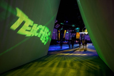Switching from last year's circular tunnel, the entrance to the cocktail area was triangular, a nod to the arrowhead-shaped emblem and superhero theme of the event. Verbs key to the organization's mission splashed across the walls.