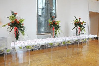 At the place card table, tall flower arrangements held green cymbidium orchids, foliage, and orange amaryllis blossoms.