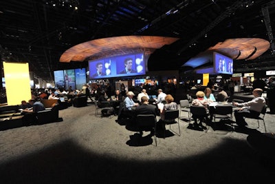 In the networking lounge, attendees could watch and listen to the keynote addresses on 18- by 60-foot screens, while also getting work done at their choice of tables or lounge seating equipped with power sources.