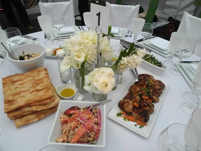 As a counterpoint to the wildflowers and grasses used in other parts of the decor, the tabletop centerpieces comprised delicate arrangements of lily of the valley, white peonies, viburnum, French tulips, green parrot tulips, ranunculus, Star of David, and hyacinth. The dinner was served family-style.