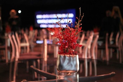 Simple, monochromatic floral arrangements in silver vessels topped tables.