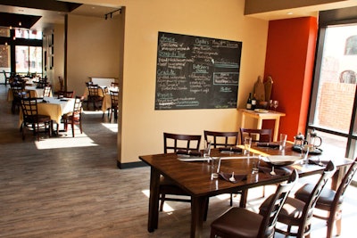 The front of the open kitchen has an eight-top table and a large blackboard that lists the day's menu. In the future, the restaurant will use this area for cooking classes.