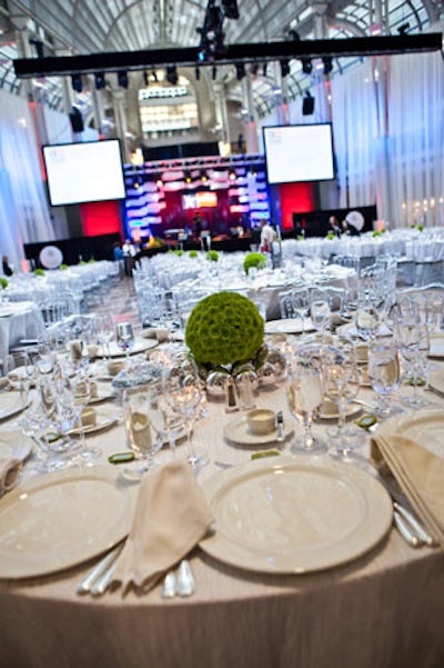 Encore Decor used all-white linens and place settings for the dinner tables, accented by bright green floral arrangements surrounded by silver balls at the base.