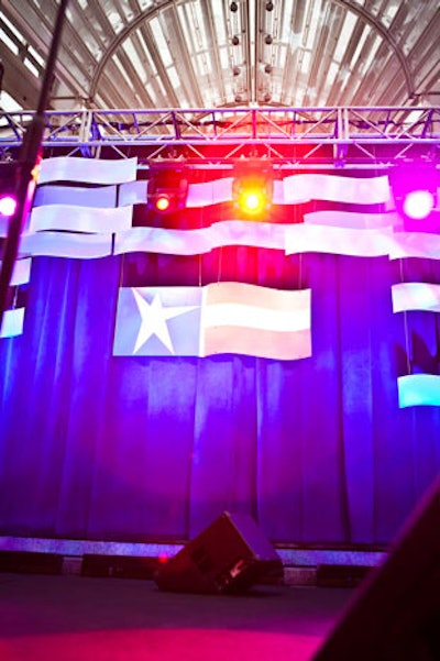 The stage stood out among the all-white event with its bright blue drape, red and blue lighting, and American flag-style suspended banners.