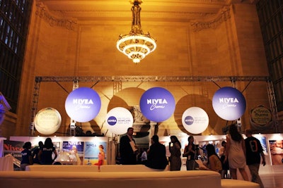 Circles figure prominently in the design of the promotional space, taking a cue from Nivea's signature blue tin. In the rear, large circular signs hang from a truss.