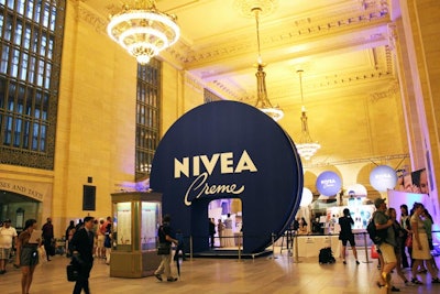 In the west wing of Grand Central Terminal's Vanderbilt Hall, the Nivea 100 Year House opened on Monday and runs through Friday. As a fun way to brand the entire space, the entrance is an oversize replica of the brand's signature cream tin, with a doorway cut into the bottom.