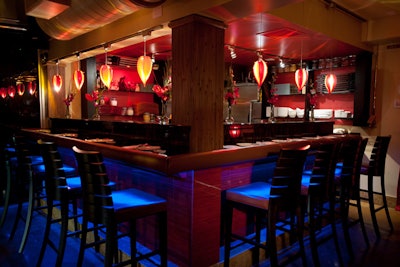 Buddha Sky Bar's sushi bar is decorated with marble, wood, and tile lit up with blue and red hues from both down and suspension lighting.