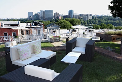 DC Rental provided rattan furniture set up throughout the lawn with white cushions and pink and green pillows.