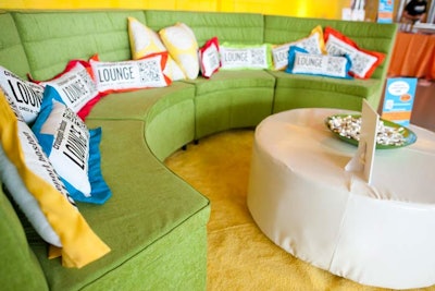 A colorful lounge area held throw pillows branded with the host venue's name.