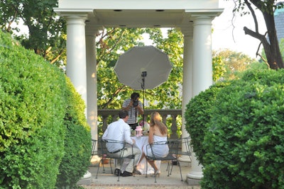 Storyteller Danny Harris setup a mock-photo shoot in the gazebo during the reception with guests posing at a green-inspired dinner table set with plates full of rocks, sticks, and leaves. The photos are being compiled into a digital short video.