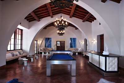 The billiard room boasts cathedral ceilings, wood paneling, and modern furnishings accented by hues of blue and white.