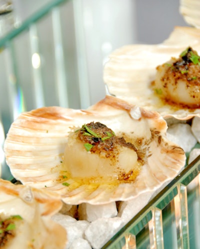 A Joy Wallace Catering Production & Design Team's executive chef, Elgin Woodman, has created sea scallops with a panko crust and citrus butter presented in a seashell. This is served over a bed of hot rocks with hidden sternos underneath.