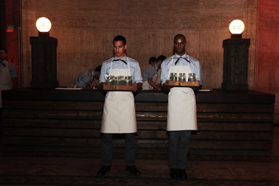 Bars, fashioned from wood and topped with a leather surface and 1950s-style globe lamps, stood on either of the hall. The event producers integrated the clothing the waitstaff wore into the overall design of the affair, dressing the male servers in striped shirts and white aprons.