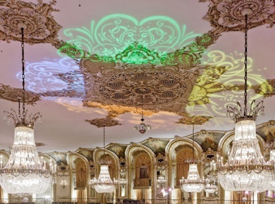 The invitation's colorful graphic lit up the ceiling of the grand ballroom. The lighting scheme was meant to enhance the already existing gold medallion.