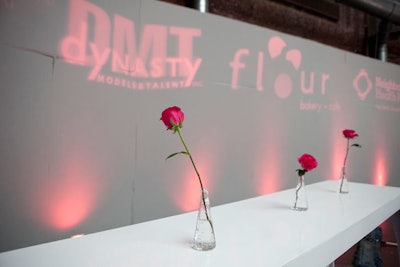 Glass vases held single pink roses, which played into the designer's logo. Sponsors' logos appeared in lighting on the walls.