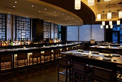 The bar and lounge just inside the entrance features community high-top table seating at dark wood tables.