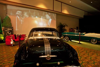 On one side of the ballroom, Spectacular Themes used set pieces to create the 'Starlite Drive-In Theatre,' with vintage vehicles set up in front of a screen showing American Graffiti.