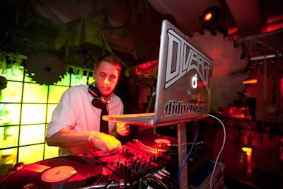 DJ Diverse spun in front of rotating saw blades and a lit-up green backdrop.