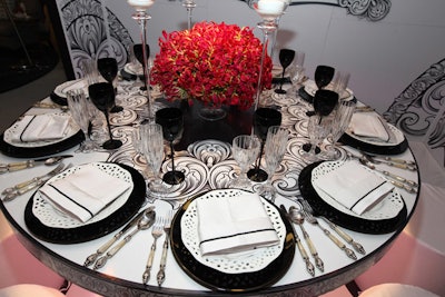 A centerpiece of red flowers popped against the black-and-white palette of the table, which was set with lacy white plates and glossy black wine glasses.