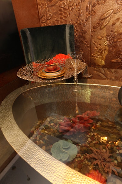 The table was fashioned from a glass-topped copper bathtub filled with water, coral, and other representations of sea life.