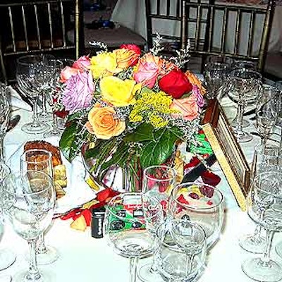 Diana Gould decorated tables with bright yellow, orange, violet and red rose bouquet centerpieces in glass bowls surrounded by rose petals.