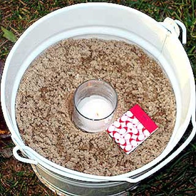 White pails filled with sand—evocative of a summer day at the beach—held votive candles and doubled as anchors for large white tent from Stamford Tents.