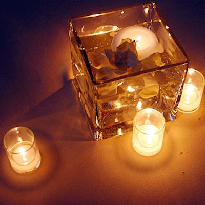 Designer Antony Todd topped tables with square glass vases filled with water, floating white candles and white rose petals.