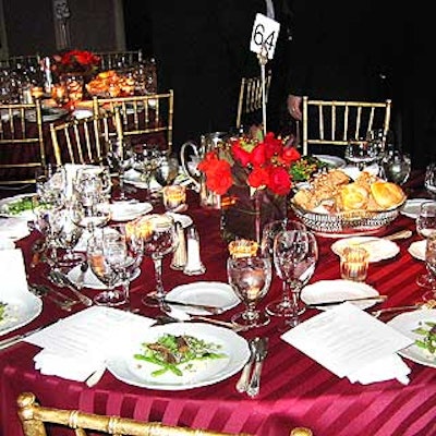 Floralia covered tables with burgundy tuxedo-striped linens and placed roses, seeded eucalyptus and pittosporum floral arrangements in square glass vases.