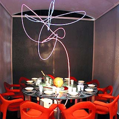 DDC designed a futuristic space around an asymmetrical curved table with orange chairs from Saporiti Italia and a hanging neon light piece that changed colors.