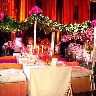 Antony Todd created a dining environment with a long banquet table paired with overstuffed cushions and a canopy of vines dotted with bunches of pink peonies. The table featured dense arrangements of more pink peonies dotted with orange flowers.