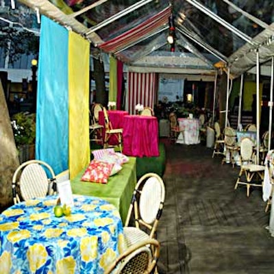 Cocktail tables topped with vibrantly colored tablecloths and paired with wicker chairs filled the tented area.