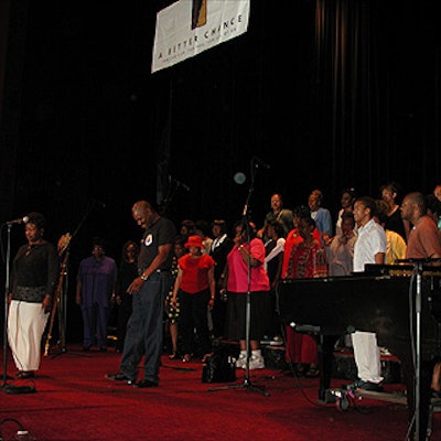The Abyssinian Baptist Church Chancel Choir practiced on the stage before the luncheon, under a sign by Ace Banner Flag & Graphics.