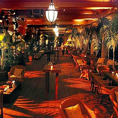 The terrace room was lined with palm plants, wicker chairs, overstuffed couches and wood cocktail tables decorated with colorful antique glass cups and small, lush flower arrangements.