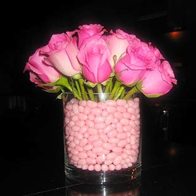 Cute floral arrangements of pink, purple and green roses in rectangular glass vases filled with matching jelly beans lined the bars.
