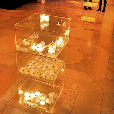 Van Wyck & Van Wyck created Lucite cubes and coffee tables filled with white gerberas, hydrangeas, candles and feathers and topped with white votives and floating orchids.