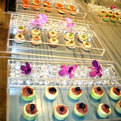 Caterwaiters served hors d'oeuvres on clear trays decorated with orchids.