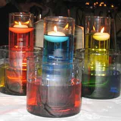 Floating candles in rainbow-colored water were used as table decor and ambient lighting.