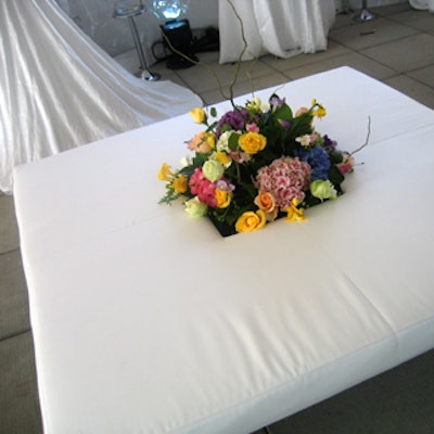 Vibrant flower arrangements emerged from the open center of white benches configured in a square.