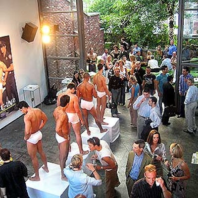 Oversized ads decorated the walls of the party's main space, where men modeling C-IN2 underwear posed on white cube podiums.