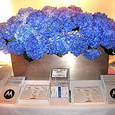 A stainless steel box filled with hydrangea decorated a table covered with Motorola product information.