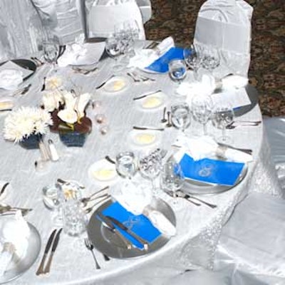 Tables and chairs were dressed in silver linens, which were topped with silver place settings.
