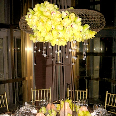 Gotham Gardens’ table featured a tall metal structure topped off with a round form decorated with a swath of green orchids and adorned with hanging crystal pendants.