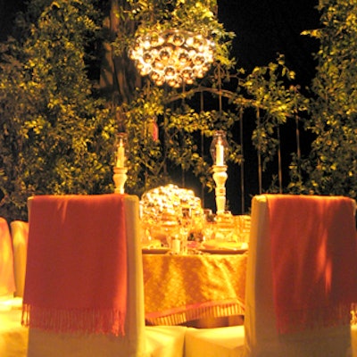 The elegant table designed by David Stark and Avi Adler for Elle Decor mixed orange throws over the backs of chairs with pale beige covers. A delicate floral pattern dominated the tablecloth.