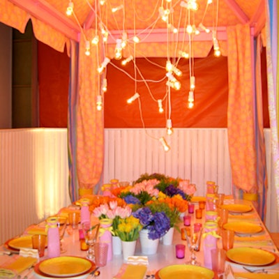 The table from SeaCloth and John Rosselli & Associates was a peppy mix of pinks, yellows, and blues with its striped canopy, short white vases of brightly colored flowers, and pretty plates, napkins and stemware.